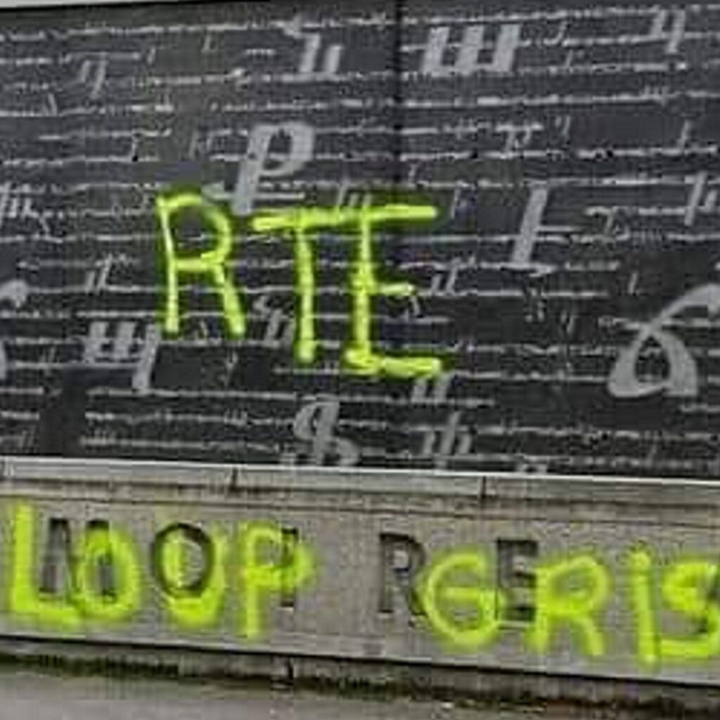 Graffiti defacing an Armenian memorial in Paris, France, with yellow spray paint, including the letters 'RTE' and references to 'LOOP GRIS' (Grey Wolves), a Turkish ultranationalist group. The vandalism is part of an anti-Armenian attack amid rising ethnic tensions. The background features Armenian script on a dark wall, partially obscured by the graffiti.