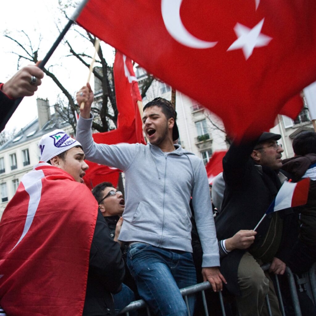 Turkish nationalists wave Turkish flags and shout slogans during a demonstration in France following U.S. President Joe Biden’s recognition of the Armenian Genocide. Reports indicate that some protesters chanted anti-Armenian slogans, including 'death to Armenians,' escalating tensions between Armenian and Turkish communities in France.