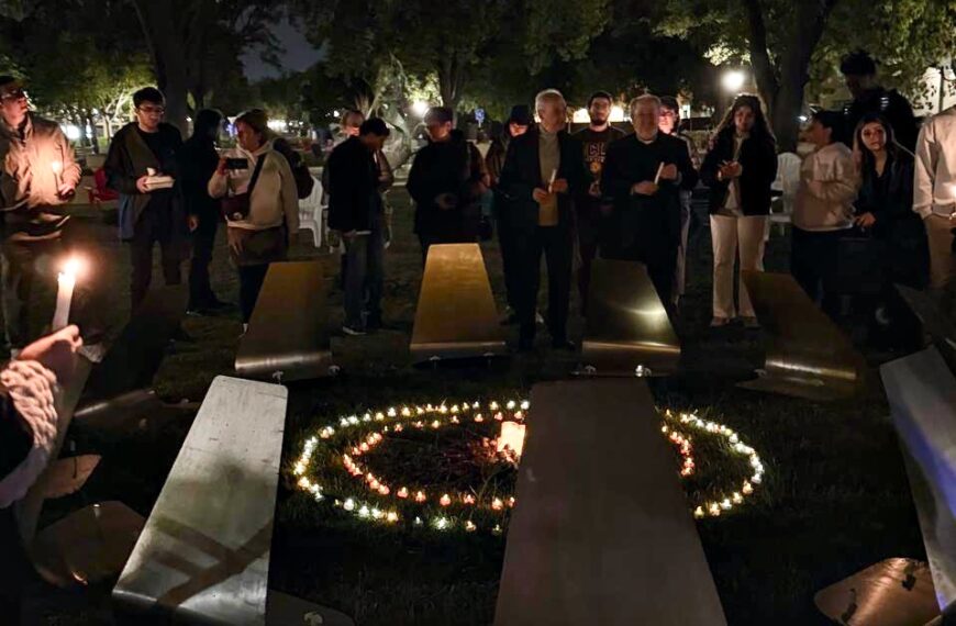 Stanford students holding candles around a symbolic reconstruction of the Tzitzernagapert Armenian Genocide Memorial during a nighttime vigil.