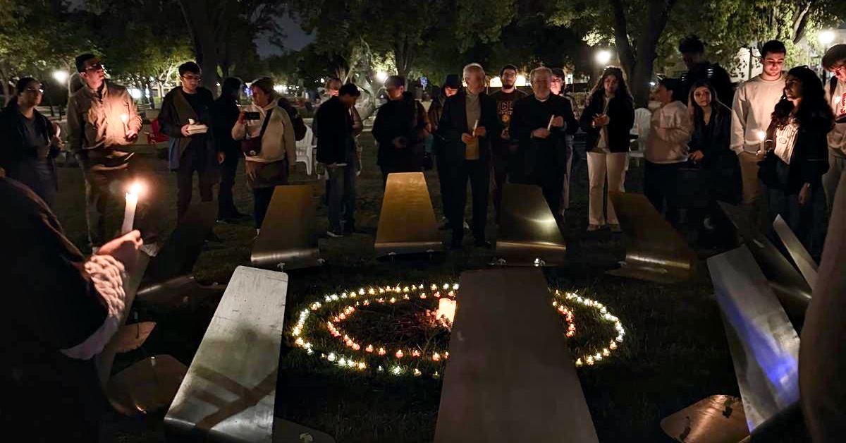 Stanford students holding candles around a symbolic reconstruction of the Tzitzernagapert Armenian Genocide Memorial during a nighttime vigil.