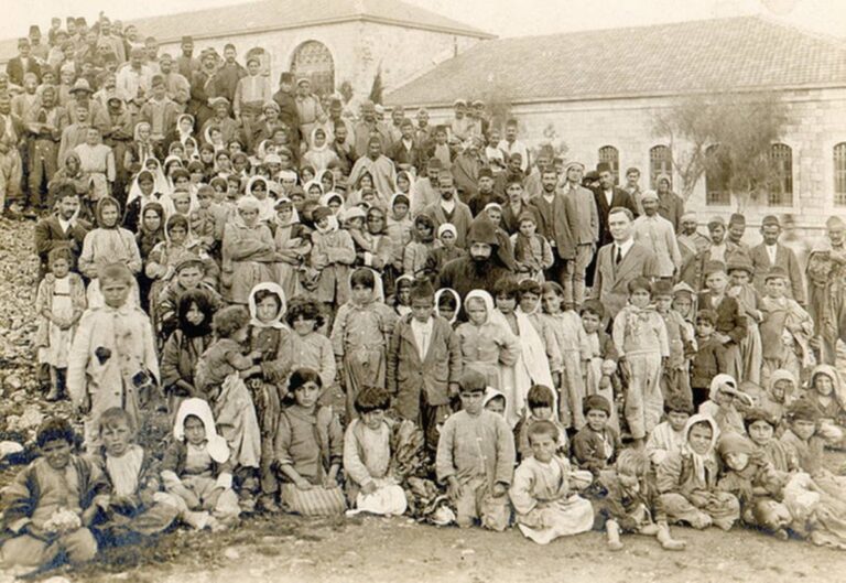 Historic photo of Armenian orphans and genocide survivors in Aleppo, 1918, posing with relief workers after surviving death marches, abduction, and forced displacement.